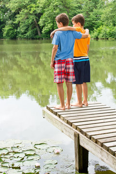 Zwei jugendliche Freunde blicken auf idyllischen Teich