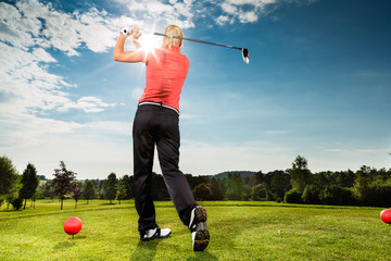 Young golf player on course doing golf swing