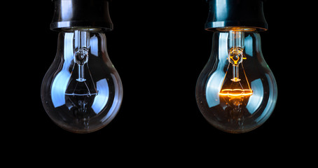 Close up light bulb and one glowing bulb on black background