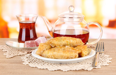 Sweet baklava on plate with tea on table in room