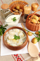 Tender young potatoes with sour cream and herbs in wooden bowl
