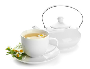 Cup and teapot of herbal tea with wild camomiles and mint,