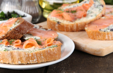 Fish sandwiches on cutting board and plate on wooden table