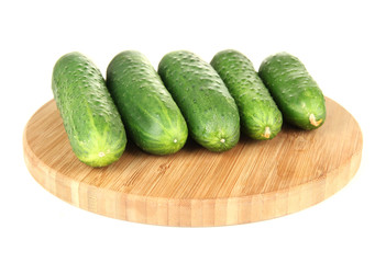 Tasty green cucumbers on wooden cutting board, isolated on