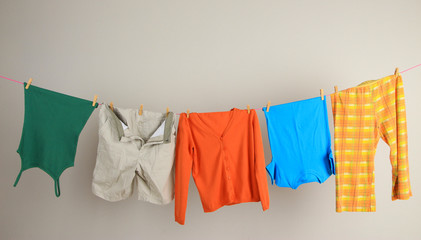 Laundry line with clothes on wall background