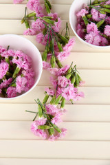 Many small pink cloves in cups on wooden background