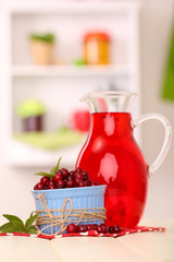 Pitcher of cranberry juice and red cranberries on table