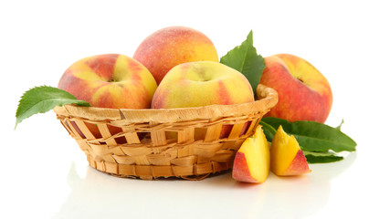 Ripe sweet peaches with leaves in basket, isolated on white