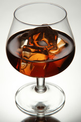 Brandy glass with ice on grey background