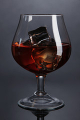 Brandy glass with ice on grey background