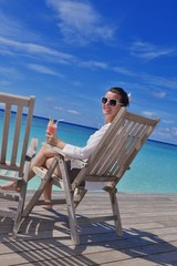 Beautiful young woman with a drink by the sea