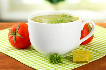 Cup of soup with bouillon cubes on wooden table