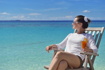 Fototapeta na wymiar Beautiful young woman with a drink by the sea