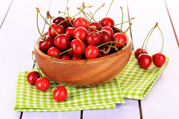 Cherry berries in bowl on wooden table close up