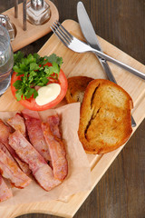 Bacon on plates on board on wooden table