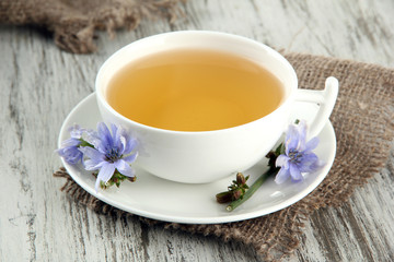 Cup of tea with chicory, on wooden background