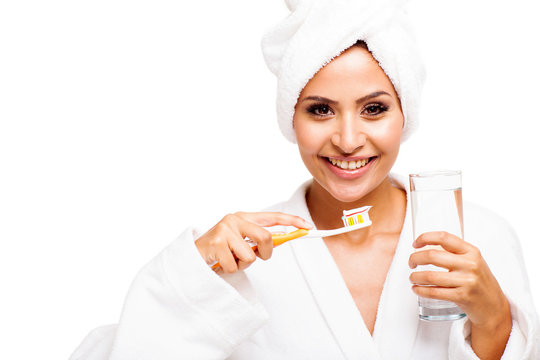 young woman in bathrobe brushing teeth