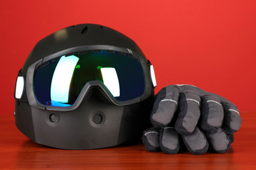 Winter sport glasses, helmet and gloves, on red background