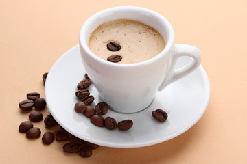Cup of coffee with coffee beans on beige background