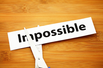 Word impossible cut to possible over wood background
