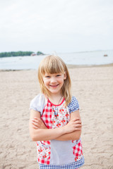 Smiling young girl at beach with arms folded