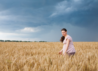 Naklejka na ściany i meble Young pregnant woman on wheat field