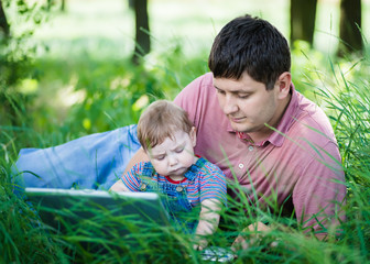 Naklejka na ściany i meble father with his son on nature with laptop