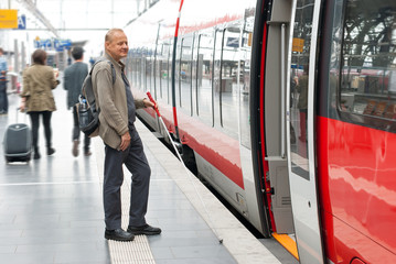 Visually impaired man boarding a train at the station - obrazy, fototapety, plakaty