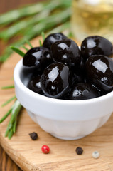 black olives and spices on a wooden board, close-up vertical