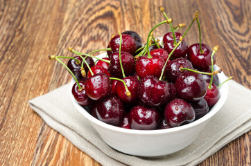 bowl of fresh cherries on a wooden background