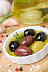 bowl with different olives in oil, rosemary and spices