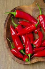 close-up of wooden bowl with red chili peppers, top view