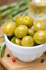 green olives and spices on a wooden board, close-up vertical