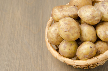 Plakat new potatoes in a basket on a gray wooden background