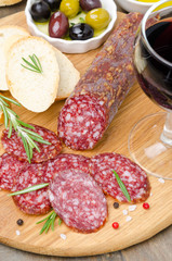 salami sliced ​​to pieces, bread, olives and a glass of wine