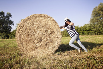 Naklejka na ściany i meble Young woman pushing a hay
