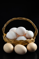 Fresh eggs in basket on black background