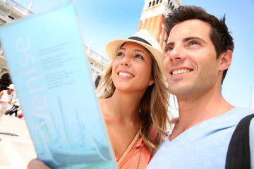 Couple reading tourist guide on San Marco place, Venice