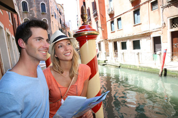 Fototapeta na wymiar Couple of tourists in Venice looking at map by canal