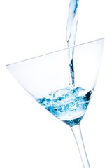 pouring a glass with blue cocktail tilted and bubbles
