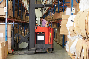 Man Driving Fork Lift Truck In Warehouse