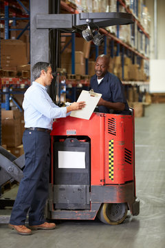 Fork Lift Truck Operator Talking To Manager In Warehouse