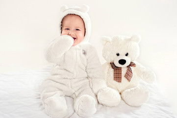 the little boy in a suit of a bear cub sits near a teddy bear