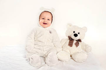 the little boy in a suit of a bear cub sits near a teddy bear