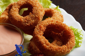 Image of meat breaded rings served with sauce