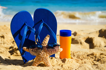 Flip flops, sunscreen and starfish on sandy beach