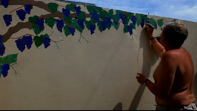 man painting vine on wall