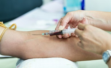 Doctor drawing blood sample from arm for blood test