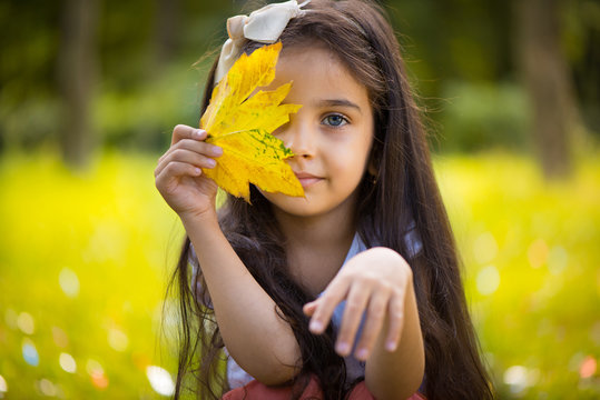 Cute hispanic girl  hiding over yellow leaf