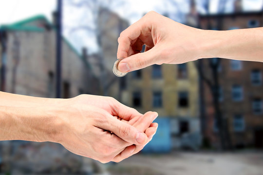 Hand gives coin to beggar on the street